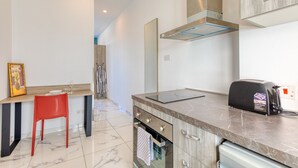 Una cocina moderna con horno empotrado, una silla roja y un tostador.