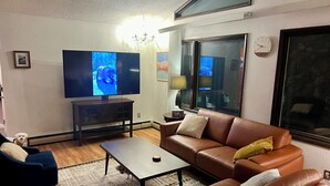 A living room with a television, sofa, coffee table, and a dog. - Urban Comfort with Northern Charm (Anchorage)