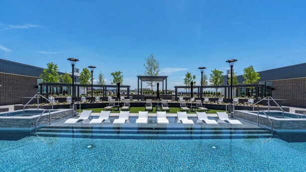 Un área de piscina exterior moderna con sillones de descanso y una estructura de pérgola.