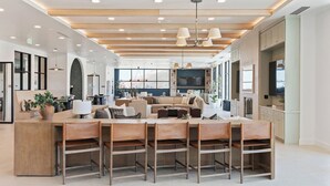 Una cocina amplia y moderna con una isla central, ventanas grandes y una zona de comedor con sillas de madera.