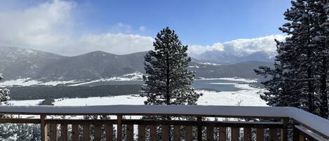 A snow-covered deck with a view of a lake and mountains.