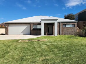 Stylish home with a garage and driveway access, set amidst a beautifully maintained lawn and garden.