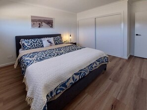 Cozy retreat with a large bed, patterned bedspread, and framed artwork.