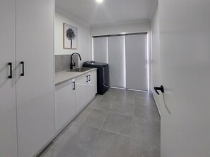 Kitchen features a sink, cabinetry, and a dishwasher, with a sliding door leading to a balcony.