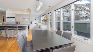 A modern kitchen with a central island, bar stools, and a dining table. - Pet-Friendly Penthouse with Shared Hot Tub (Telluride)