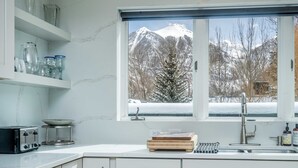 A kitchen with a window view of snow-covered mountains. - Pet-Friendly Penthouse with Shared Hot Tub (Telluride)