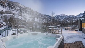 A hot tub surrounded by a wooden deck, with snow-covered mountains in the background. - Pet-Friendly Penthouse with Shared Hot Tub (Telluride)