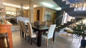 A spacious dining area with a large table and chairs, a kitchen in the background, and a staircase leading to an upper level. - Quiet Algarve villa near Albufeira & branches with prívate pool BBQ terrace (Algoz)