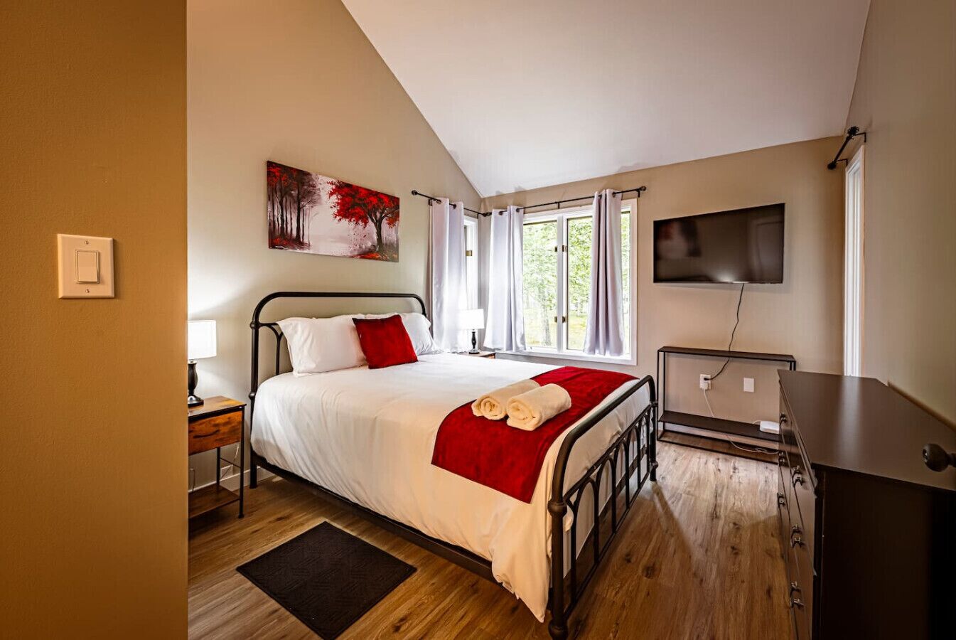 Une chambre à coucher avec un lit, un tableau, une télévision et un bureau.