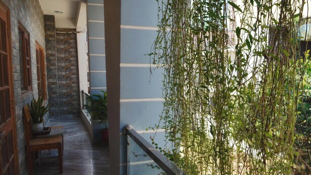 A balcony with a stone wall, a wooden bench, and potted plants. - 15 minutes to the Harkipauri! Manstays 3 bedroom condo with Balcony & parking! (Haridwar)
