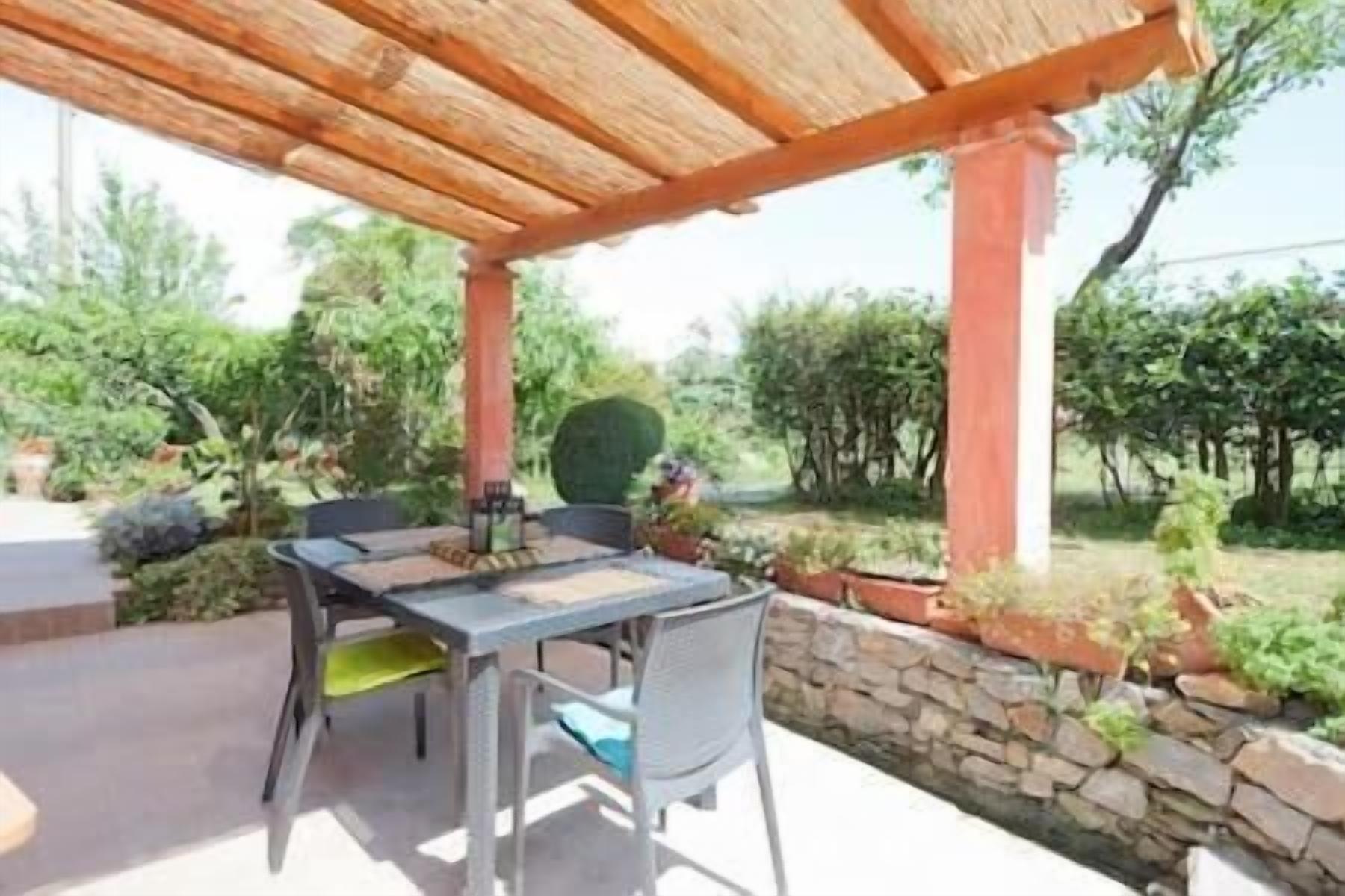 Patio esterno con tavolo e sedie, un muro in pietra e piante in vaso.