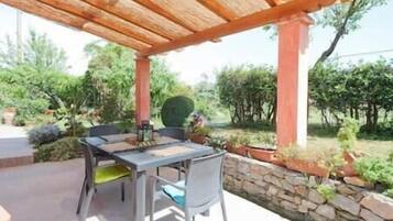 Patio esterno con tavolo e sedie, un muro in pietra e piante in vaso.