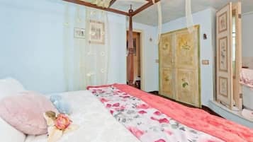 Un dormitorio con una cama con dosel, cubrecama floral y un espejo grande en la pared.