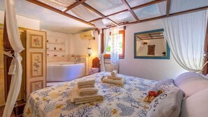 A bedroom with a bed, a bathroom, and a canopy bed. - la casa fra gli ulivi (Montemarcello)