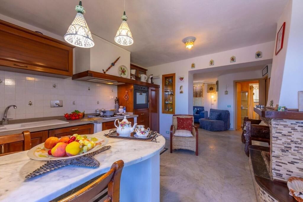 A kitchen with a marble countertop, wooden cabinets, and hanging Moroccan-style lamps.
