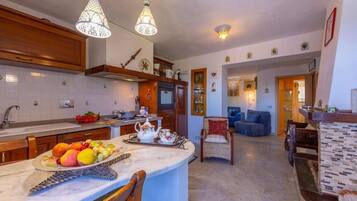 A kitchen with a marble countertop, wooden cabinets, and hanging Moroccan-style lamps.