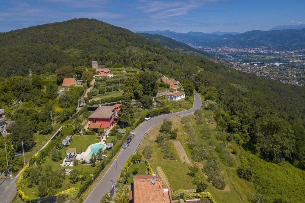 A hilly landscape with a winding road, houses, and a swimming pool.
