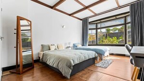 Un dormitorio con una cama grande, un armario de madera, un escritorio y una ventana que da a zonas verdes.