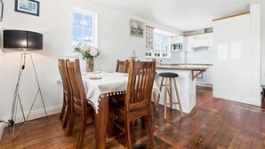 Un comedor con una mesa y sillas de madera, una lámpara de pie y un jarrón con flores.