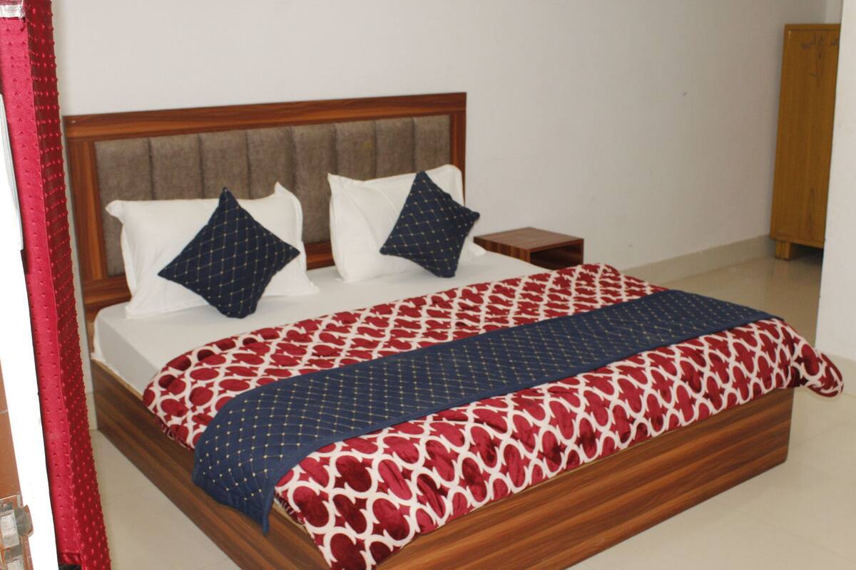 A bed with a patterned bedspread, two pillows, and a wooden headboard.