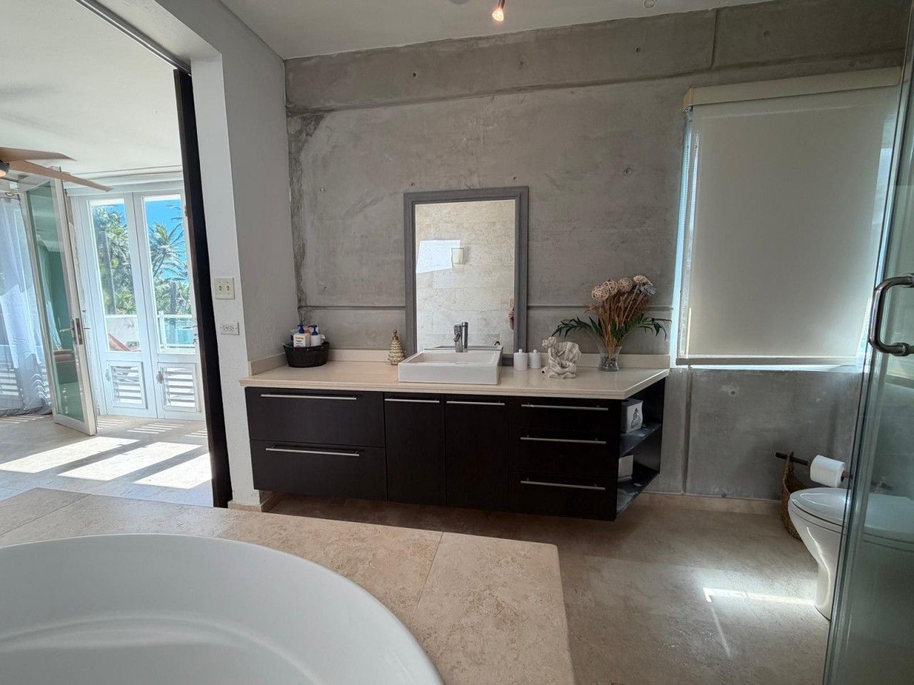 A modern bathroom with a large bathtub, a sink with a mirror above, and a toilet.