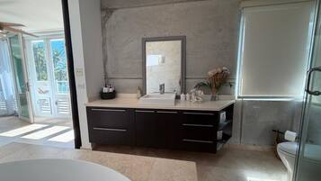 A modern bathroom with a large bathtub, a sink with a mirror above, and a toilet.
