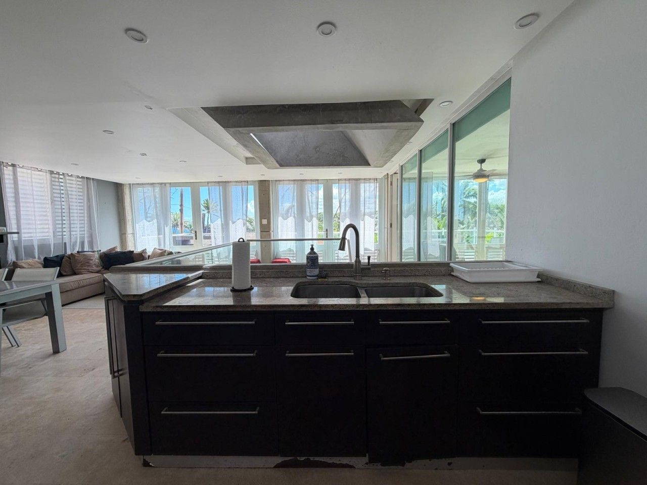 Een moderne keuken met een centraal eiland, een dubbele spoelbak en een groot raam voor natuurlijk licht.