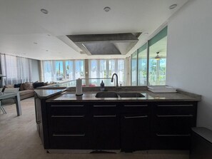 A modern kitchen with a central island, a double sink, and a large window providing natural light. - Villa Capitan | Spacious House W/ Pool & Beach (Vega Alta)