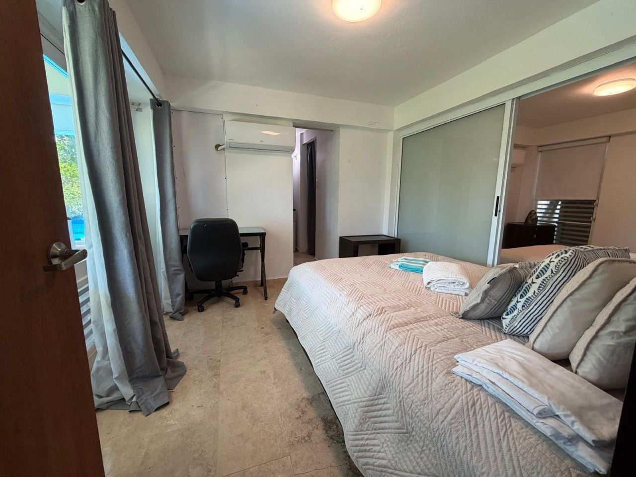 A hotel room with a bed, a desk, and a chair.