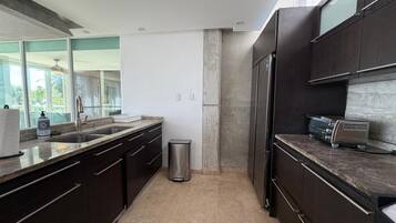 A modern kitchen with dark cabinetry, a stainless steel trash bin, and a countertop with a toaster.