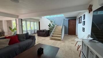 A modern living room with a sofa, coffee table, and a staircase leading to another level.