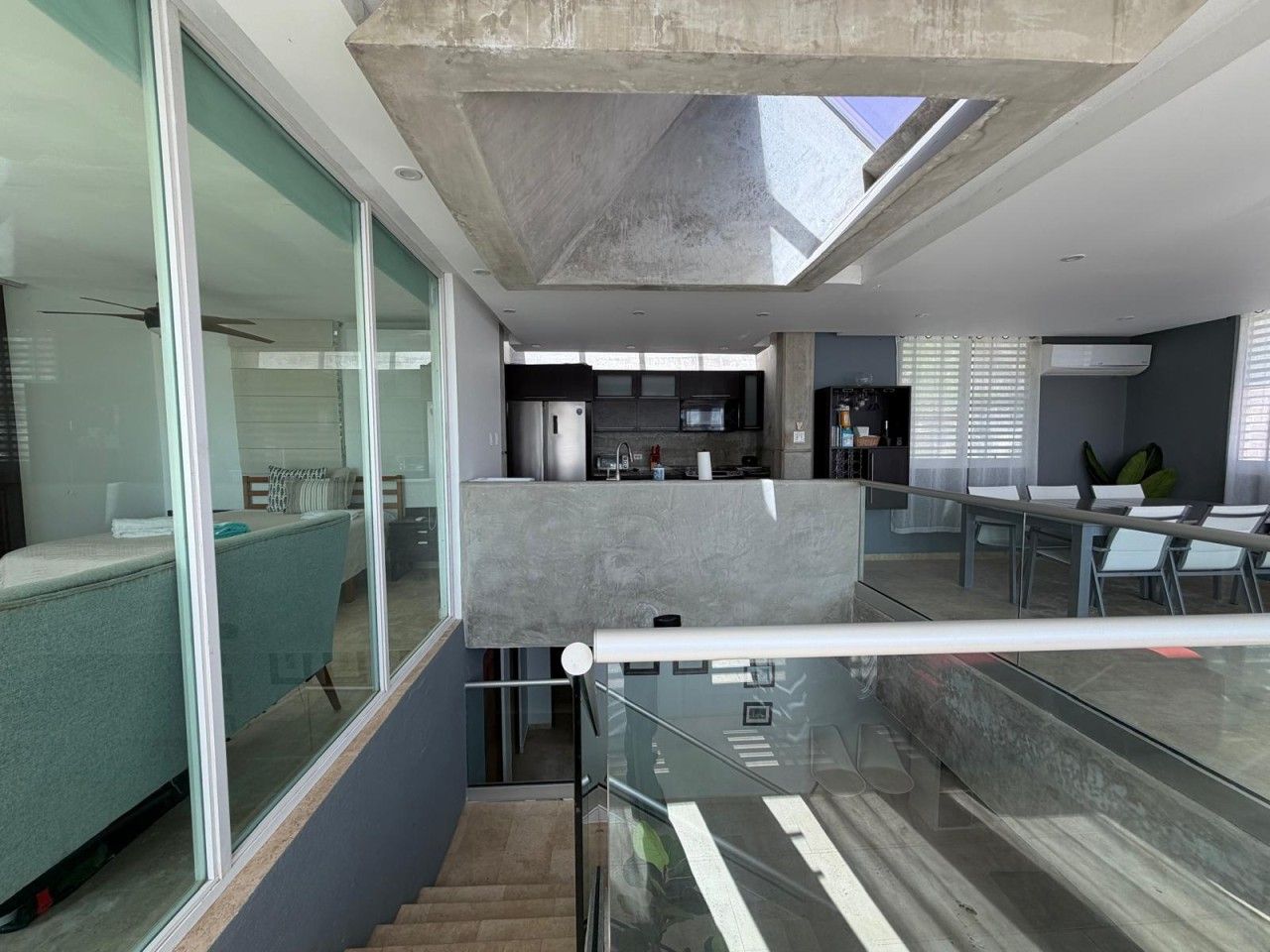 Un intérieur moderne avec un escalier en verre, un espace cuisine et un coin salon offrant une vue agréable.