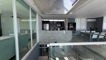 A modern interior with a glass staircase, a kitchen area, and a seating area with a view.