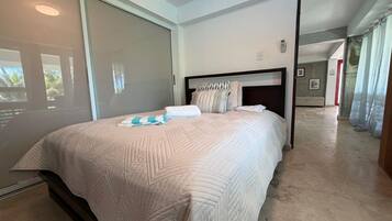 A bedroom with a large bed, a headboard, and a sliding glass door leading to a balcony.