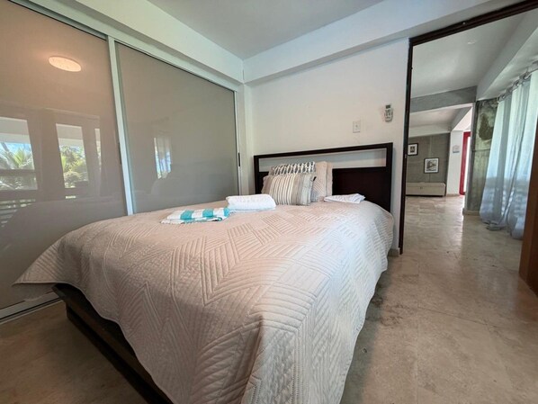 A bedroom with a large bed, a headboard, and a sliding glass door leading to a balcony.