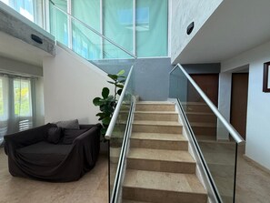 A modern interior with a staircase, a glass railing, a sofa, and a plant. - Villa Capitan | Spacious House W/ Pool & Beach (Vega Alta)