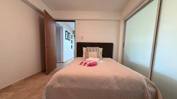 A bedroom with a bed, a door, a wall, and a window.