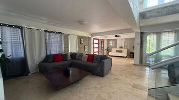 A spacious living area with a sectional sofa, a coffee table, and a staircase leading to an upper level.