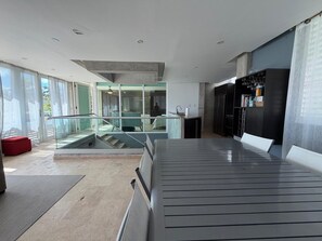 A modern interior with a glass railing, a red bench, and a kitchen area. - Villa Capitan | Spacious House W/ Pool & Beach (Vega Alta)