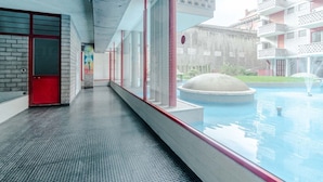 Un edificio moderno con piscina, puertas rojas y un muro de ladrillo.