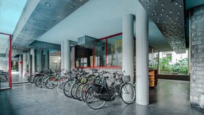 Un área de estacionamiento techada para bicicletas con varias bicicletas, un diseño arquitectónico moderno y vistas al exterior.