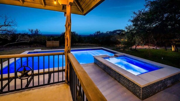 A pool area with a wooden deck and a view of the ocean.