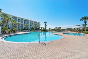 A hotel with a large swimming pool, palm trees, and a gazebo.
