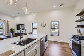 Una cucina moderna con un'isola grande, elettrodomestici in acciaio inossidabile e illuminazione a sospensione.