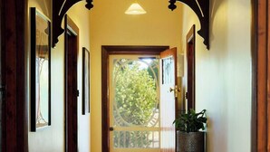 Un couloir avec une porte en bois, une plante en pot et des tableaux encadrés accrochés aux murs.