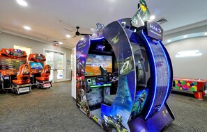 A gaming arcade with multiple racing and shooting games, including a large Halo game station.