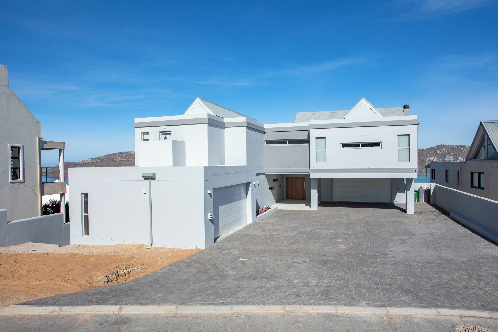A modern residential building with a garage, a driveway, and a clear blue sky.