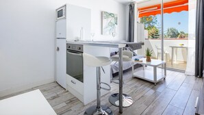 Une cuisine moderne équipée d’un four encastré, d’un micro-ondes et d’un petit coin repas avec un tabouret de bar.