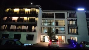 A multi-story hotel with balconies, large windows, and a well-lit entrance. - Hotel Choskor (Leh)