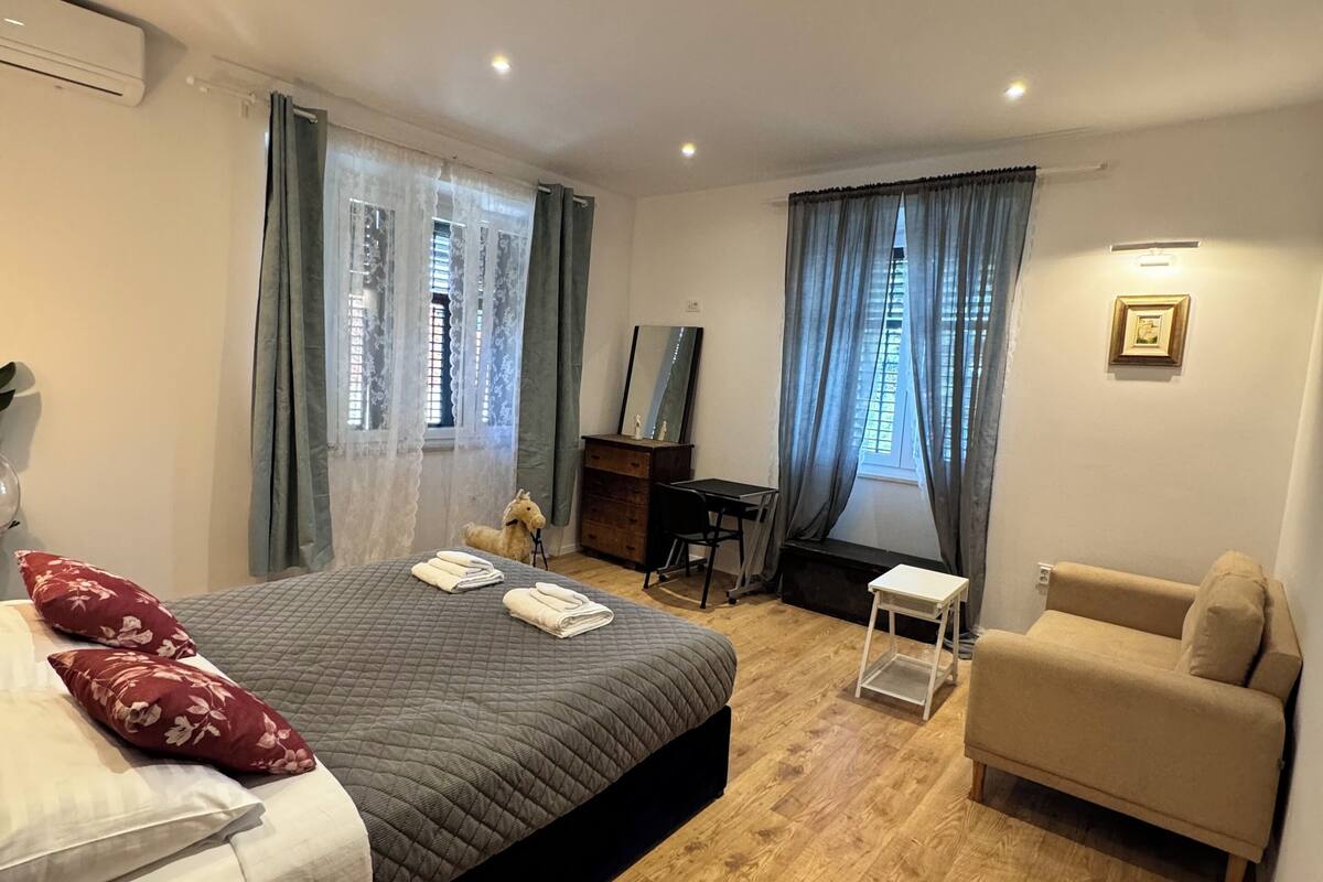 A modern bedroom with a bed, a desk, a chair, and a sofa.